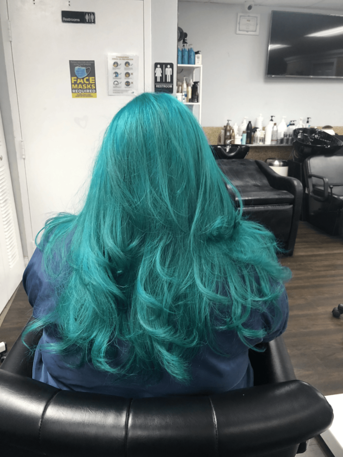 Vibrant teal hair color styled in soft curls